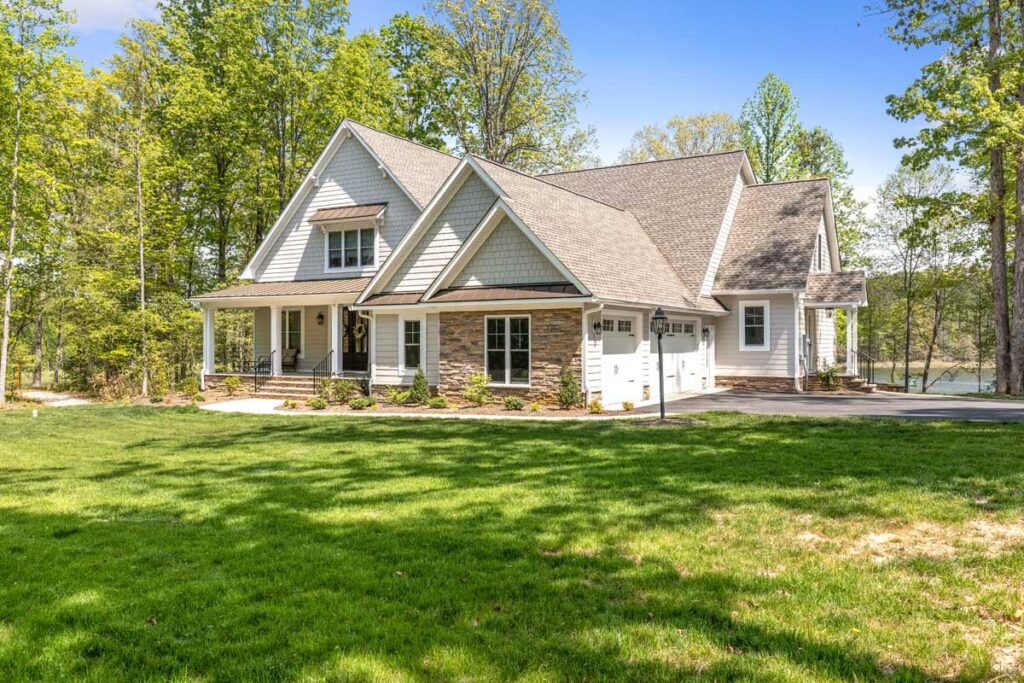 The Hogan with its covered porch and stone columns on a green lawn in Maple Grove