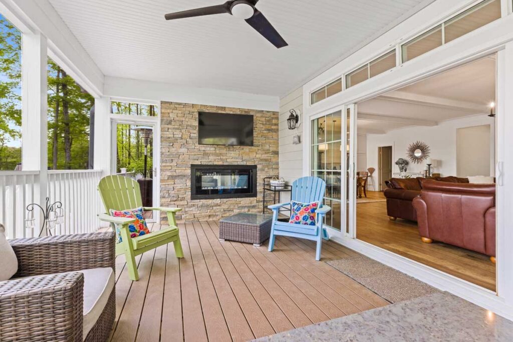 Screened porch with a stone fireplace and television in The Hogan
