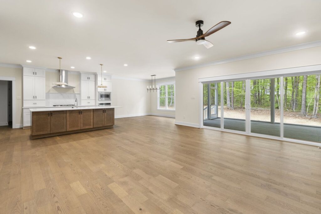Open family room with a wall of windows and hardwood floors in The McIlroy