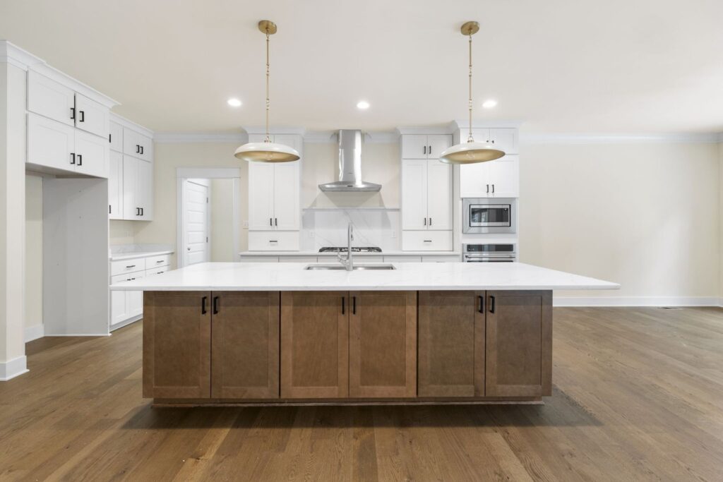 Kitchen with a wood island, white cabinets and a wood range hood in The McIlroy
