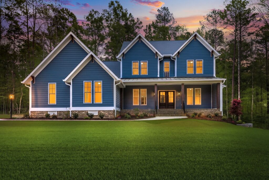 The McIlroy, a blue two-story Ridout custom home in Powhatan County at dusk with the windows lit