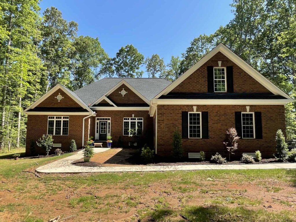 A brown brick O'Meara with a covered entry on a wooded lot