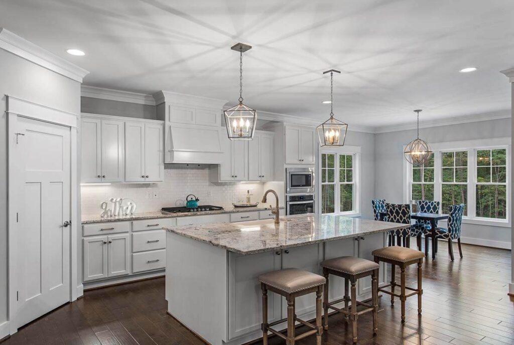 White kitchen with an island, pendant lights and stainless appliances in The O'Meara