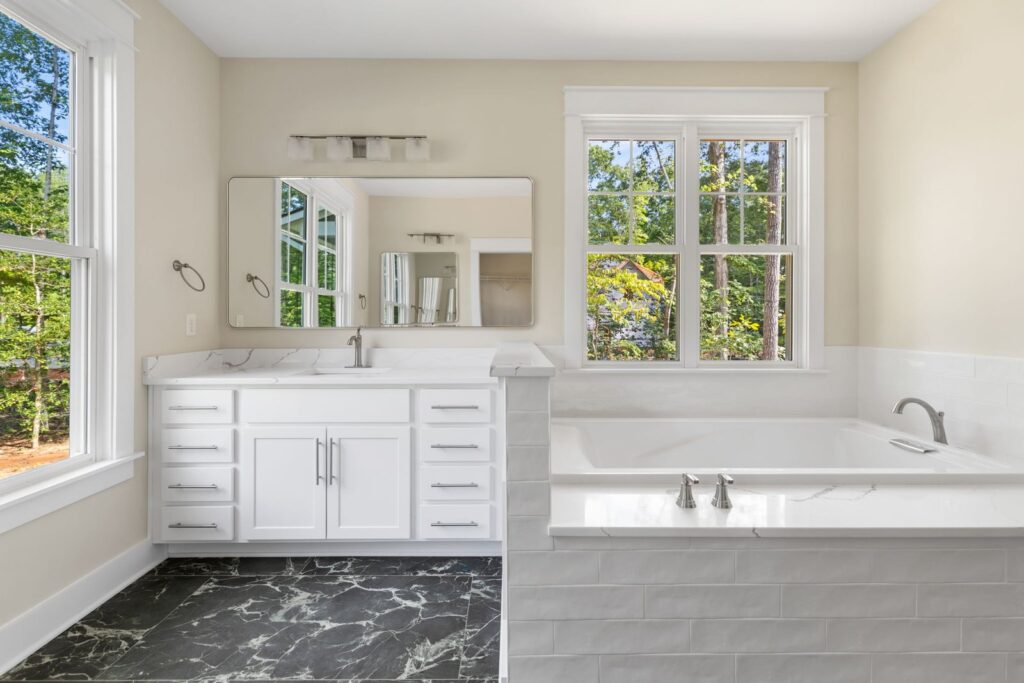 Primary bath with a white double vanity and a freestanding tub in The Palmer