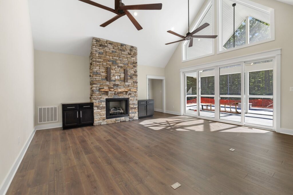 Family room with a stone fireplace, vaulted ceiling and sliding doors to the porch in The Palmer