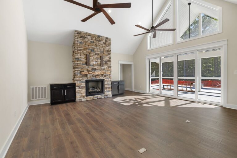 Family room with a stone fireplace, vaulted ceiling and sliding doors to the porch in The Palmer