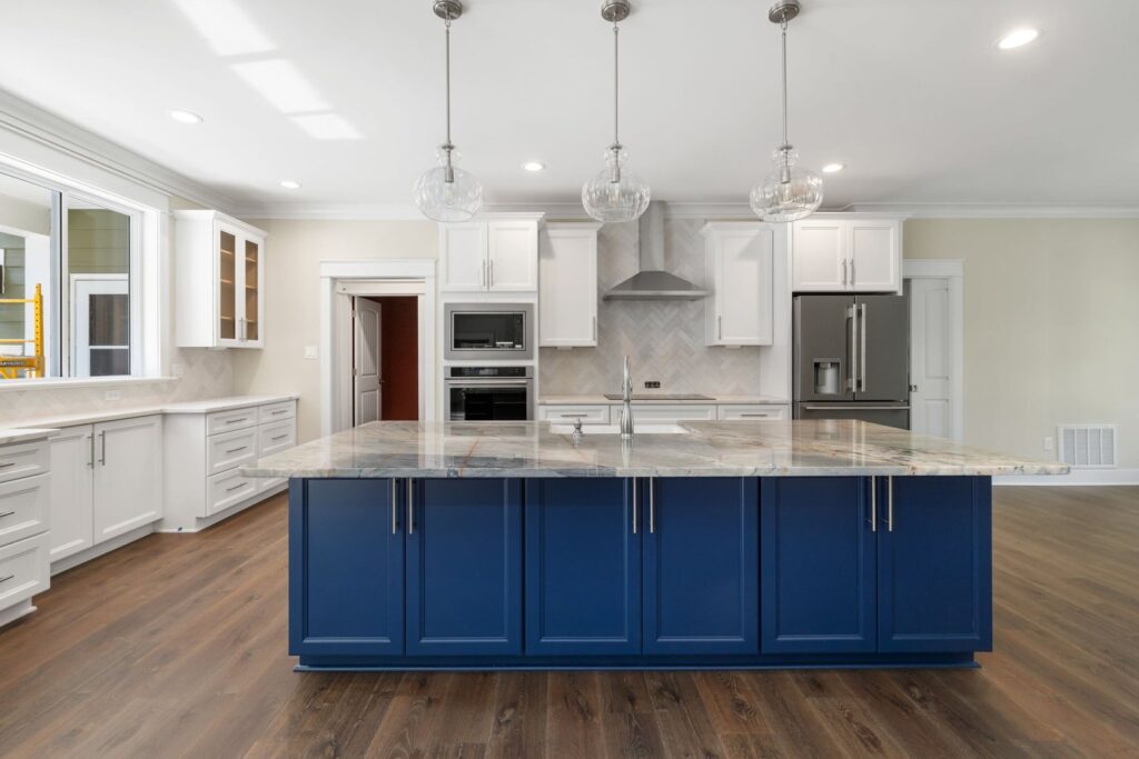 Kitchen with a navy island, white cabinets and stainless appliances in The Palmer