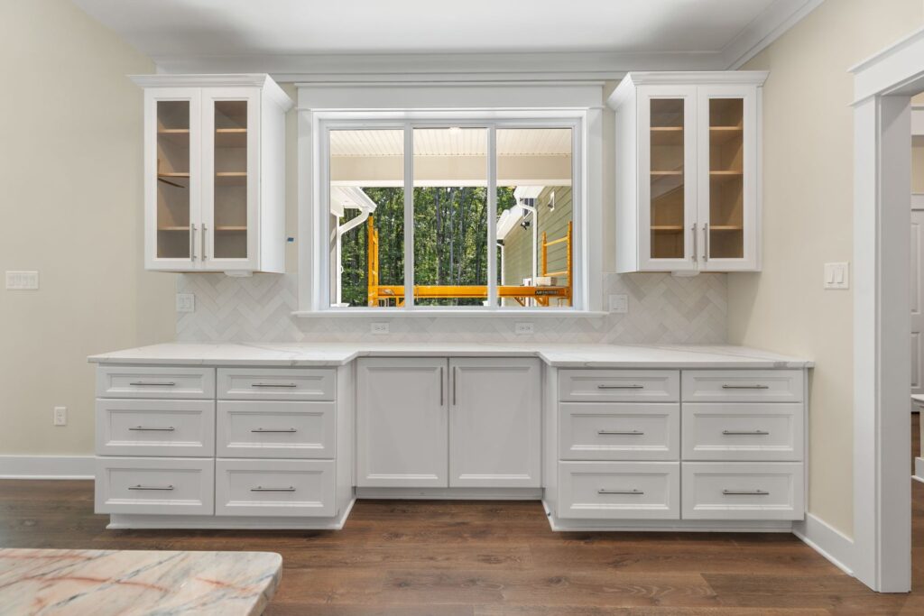 White kitchen cabinets under a wide window in The Palmer