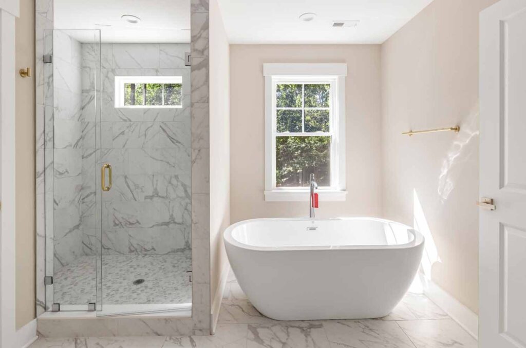 Primary bath with a marble shower and freestanding tub in The Player