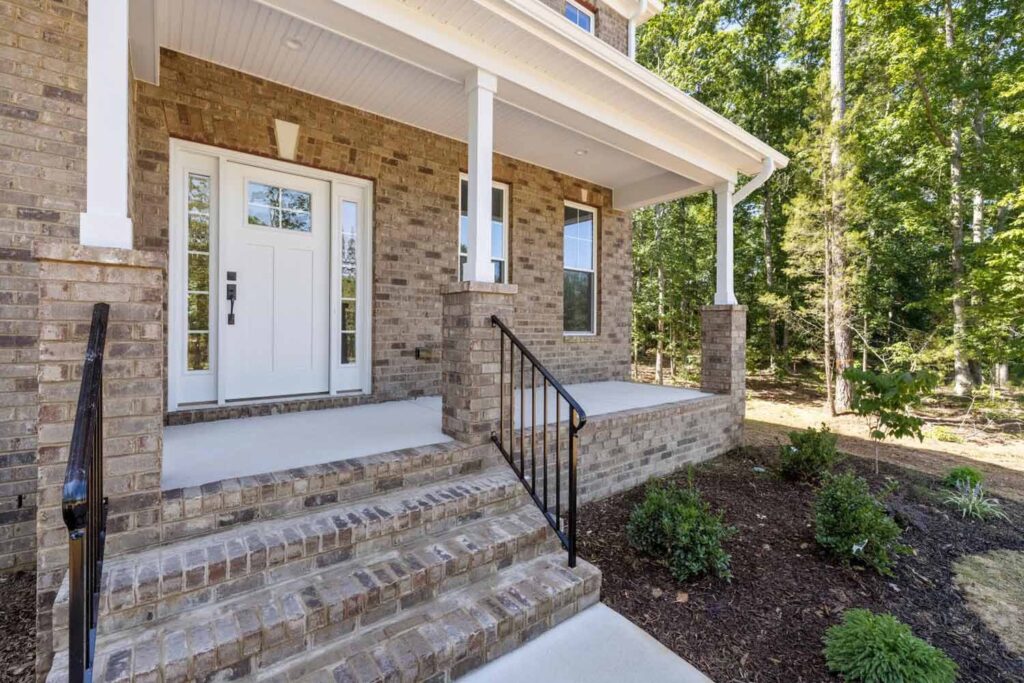 Brick front porch with a white door and iron railing in The Player