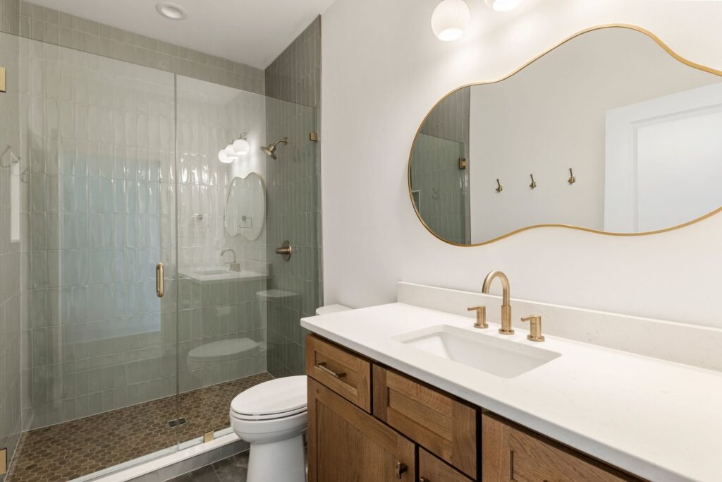 Guest bath with a wood vanity and a glass shower in The Scheffler