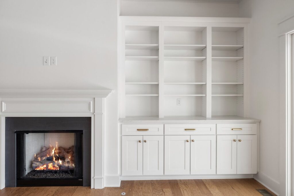 Fireplace with white built-in bookshelves and cabinets in The Scheffler