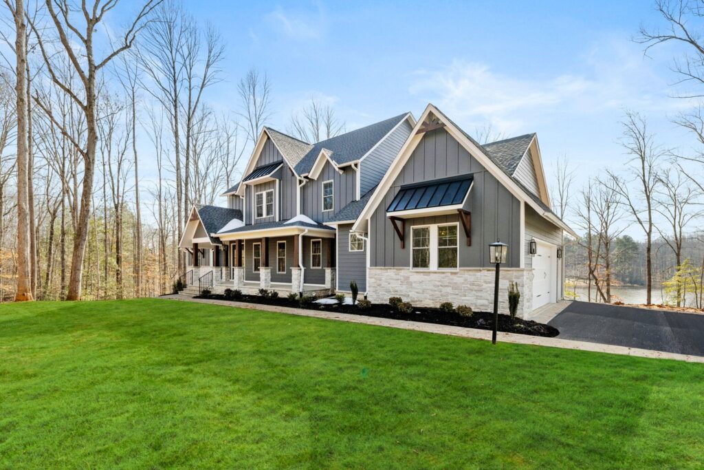 A gray craftsman-style Scheffler with a black roof and covered porch on a green lawn