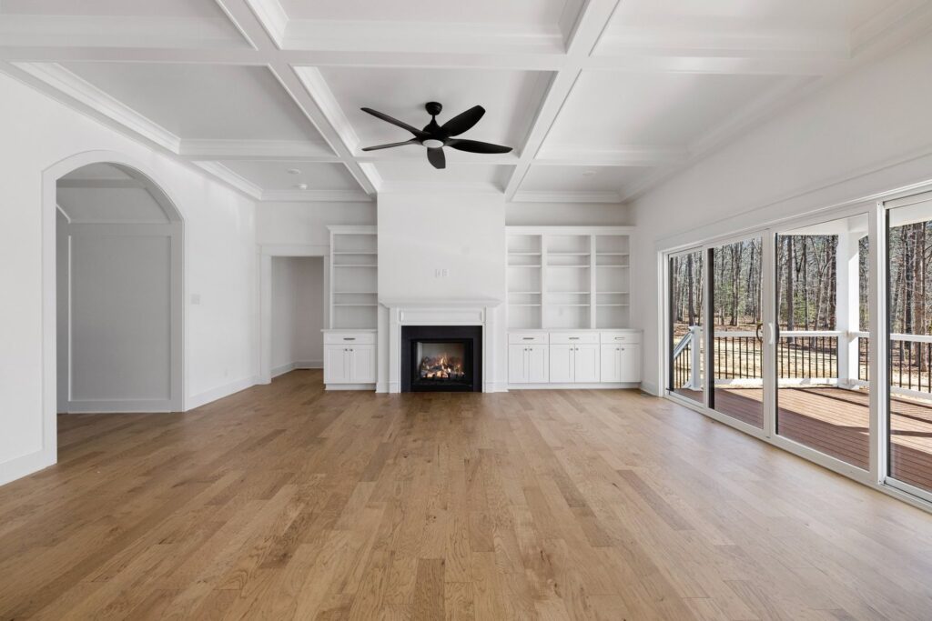 Family room with a fireplace, built-in bookshelves and sliding doors in The Scheffler