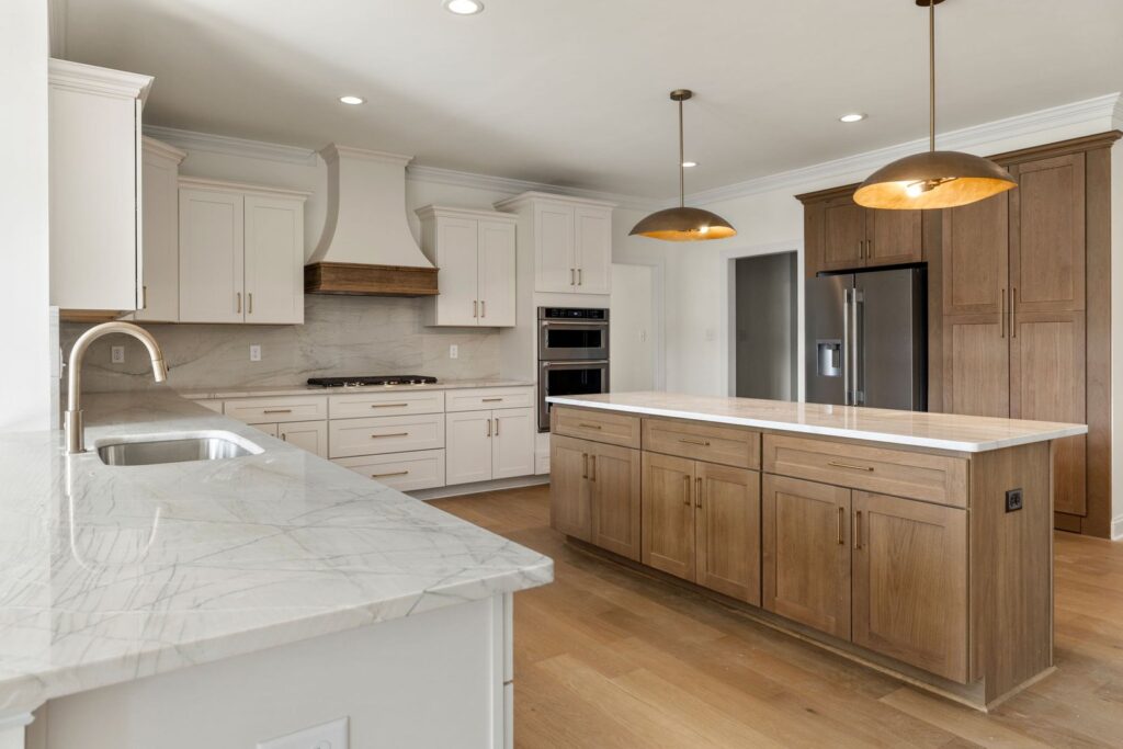 Kitchen with a wood island, white cabinets and brass pendants in The Scheffler