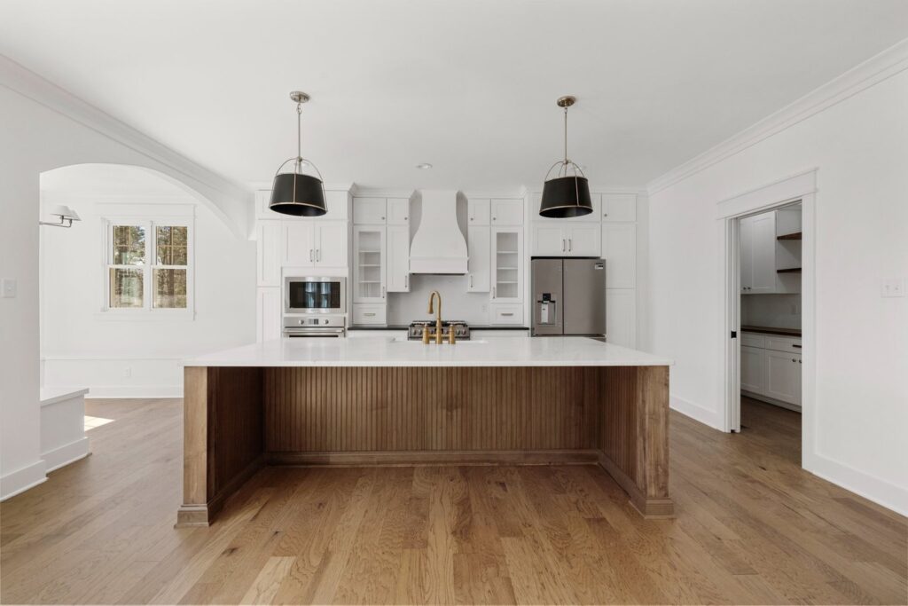 Kitchen with a long wood island and black pendants in The Scheffler