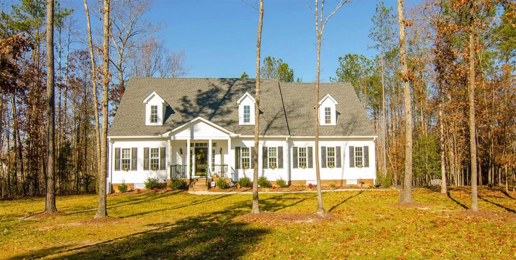 The Watson, a white farmhouse-style home among autumn trees