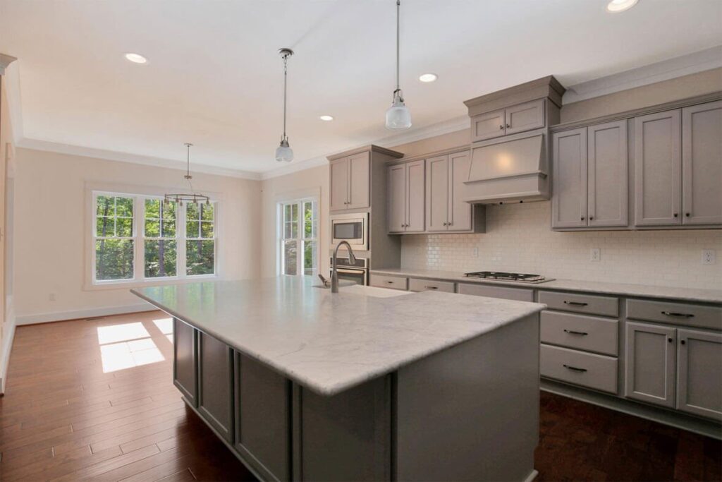 Gray kitchen with a granite island and hardwood floors in The Watson